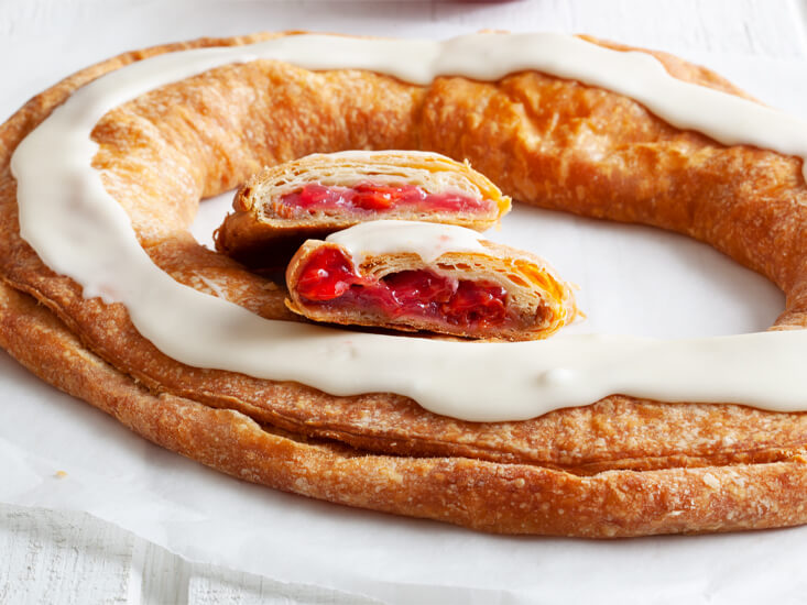 A freshly baked Kringle filled with cherries and topped with icing