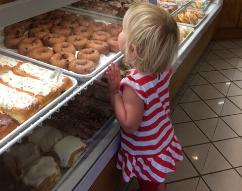 Child with donuts in bakery retail shop.