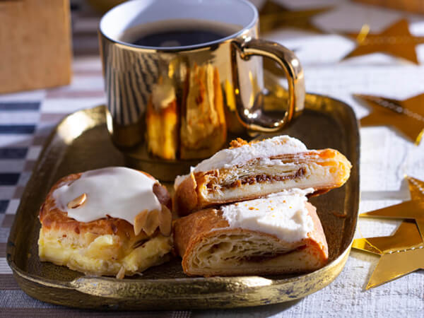 A plate of kringle and bun pastries served with a cup of coffee