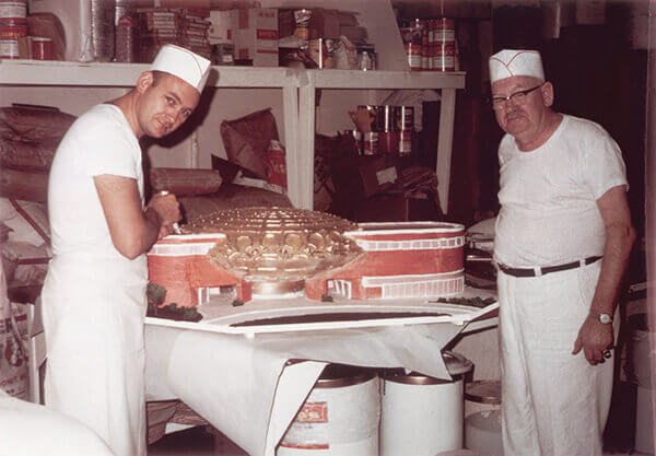Vintage photo of two bakers icing a cake at O&H Danish Bakery