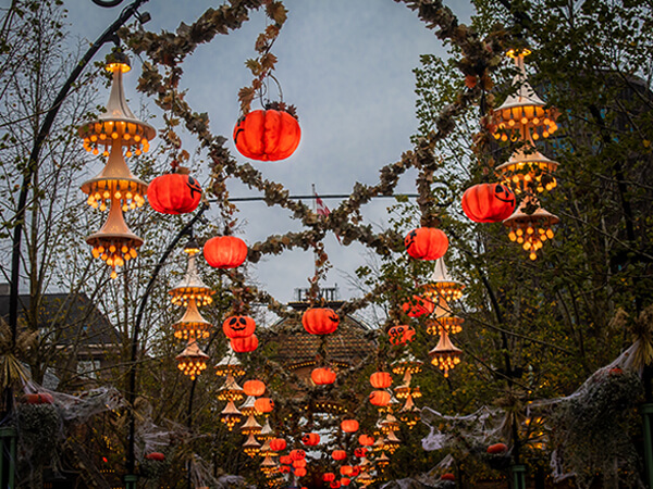 Tivoli Gardens park decorated in floating jack o'lanterns, spider webs, and autumn leaf garlands