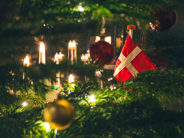 Christmas tree decorated with ornaments, lights, and Danish flags