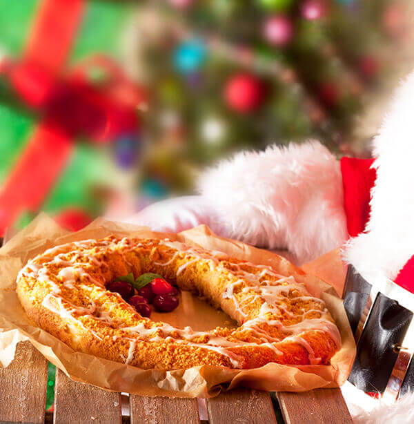 Santa holding a holiday kringle with red berries