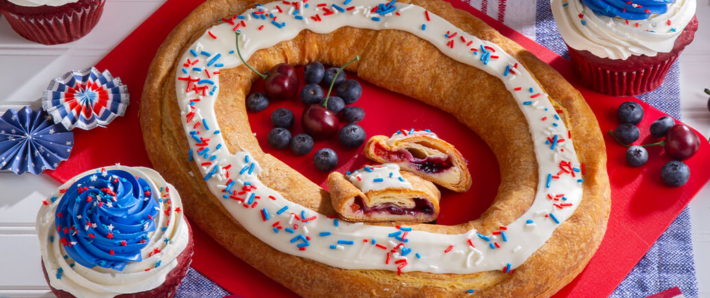Red, White, and Blue Kringle and giant Stars and Sprinkles Cupcakes desserts served on a table