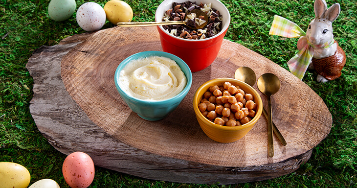 Close-up of our irresistible creamy vanilla crème layered with caramel candy pearls, and adorned with a lavish garnish of white, chocolate, and caramel curls.